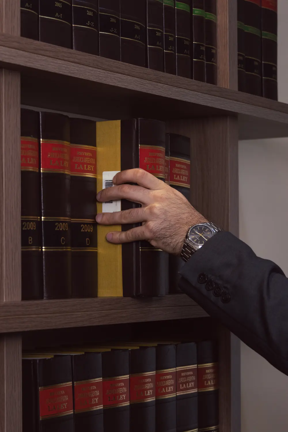 Abogado tomando un tomo de jurisprudencia de la biblioteca del estudio